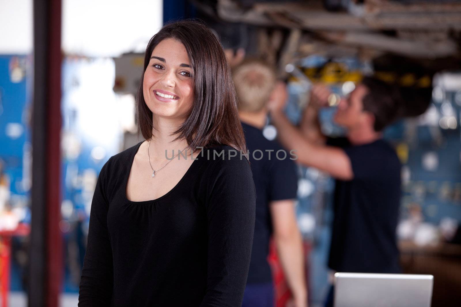 A happy woman customer in a mechanic shop, looking at the camera