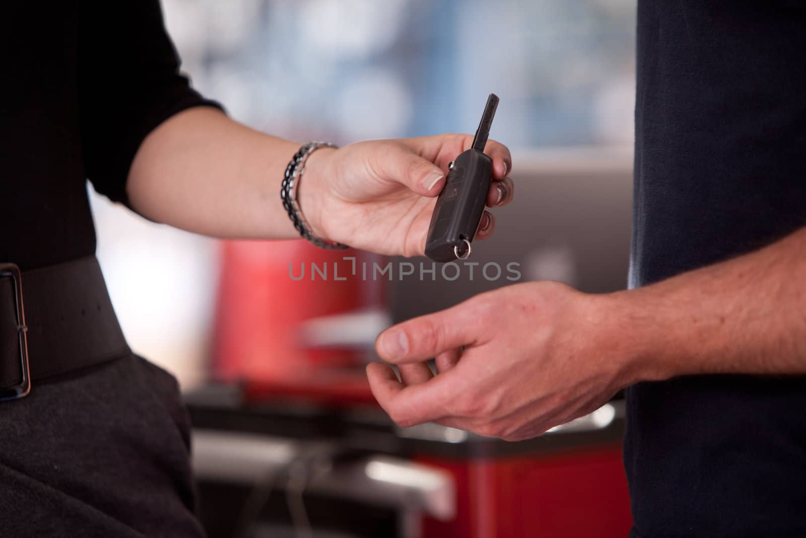 Detail of a woman deliverying a key to a mechanic