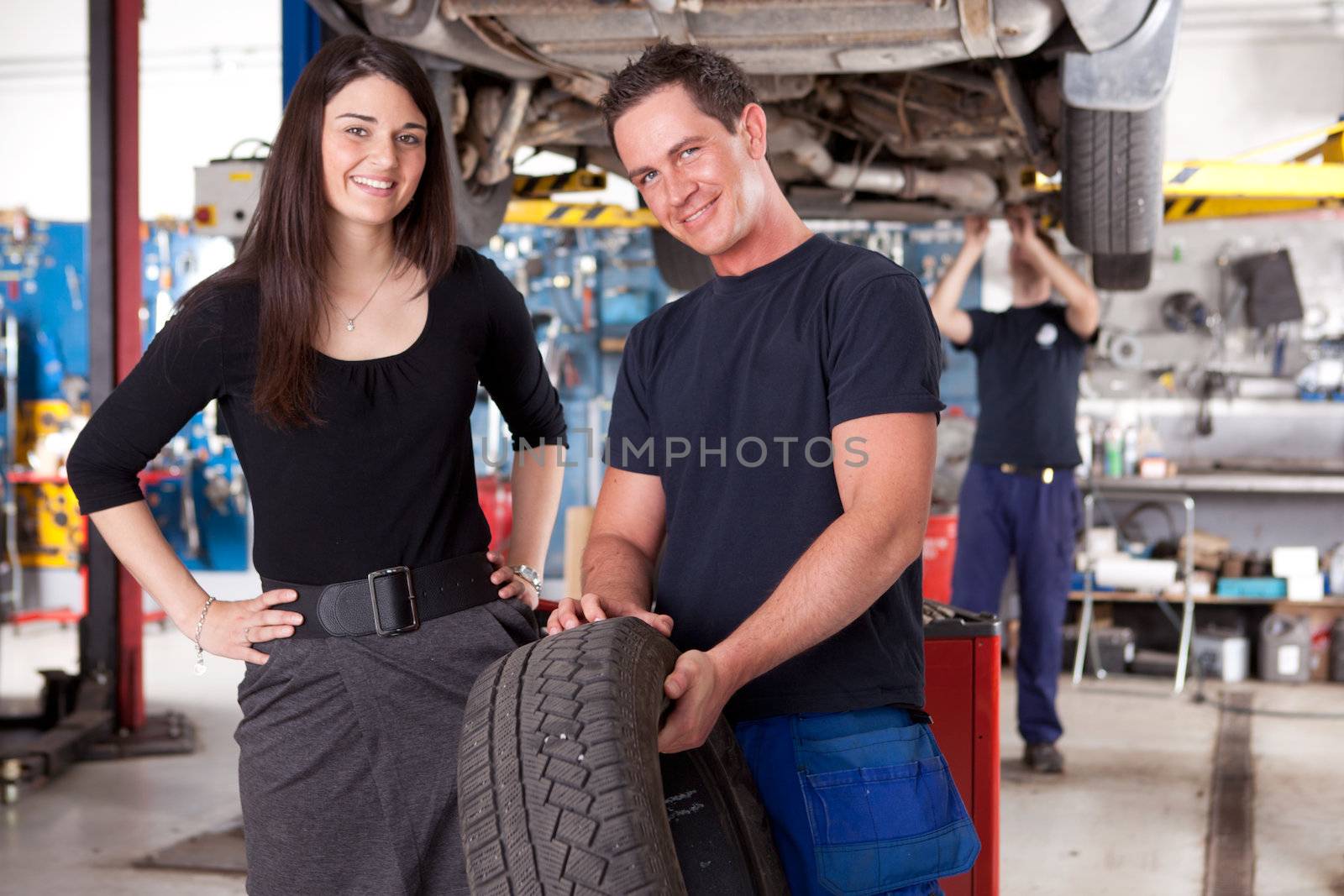 A mechanic showing a tire to a happy female customer
