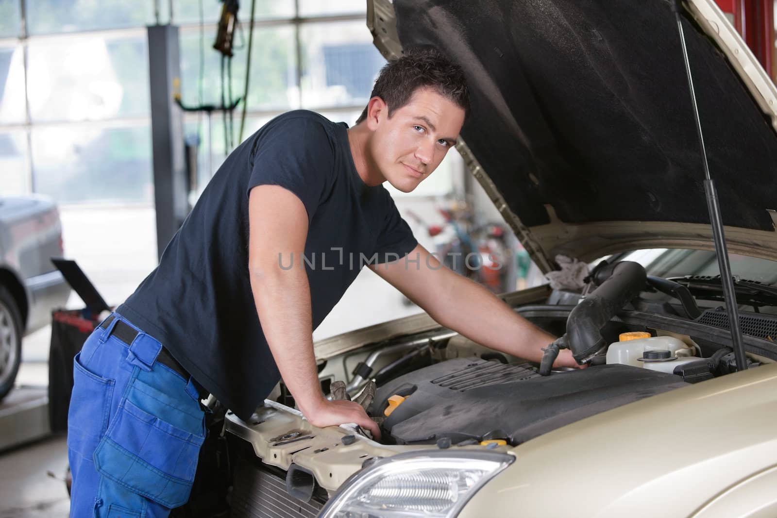 Portrait of a mechanic working on car in garage