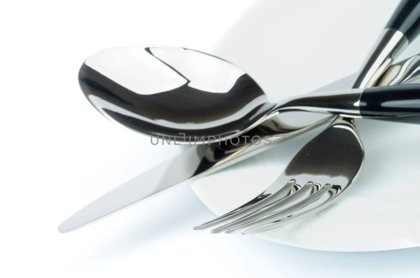 Arrangement of Silverware with Table Knife, Spoon and on White Plate closeup