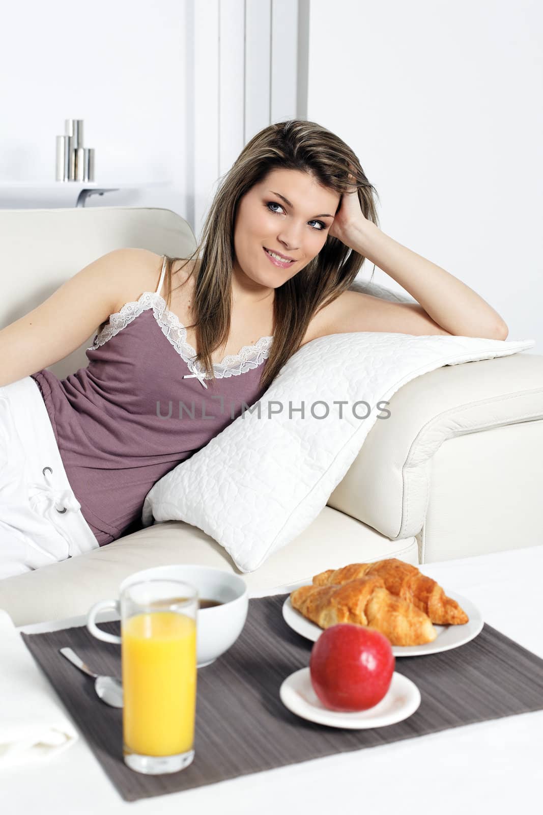 woman lying on sofa with breakfast on table