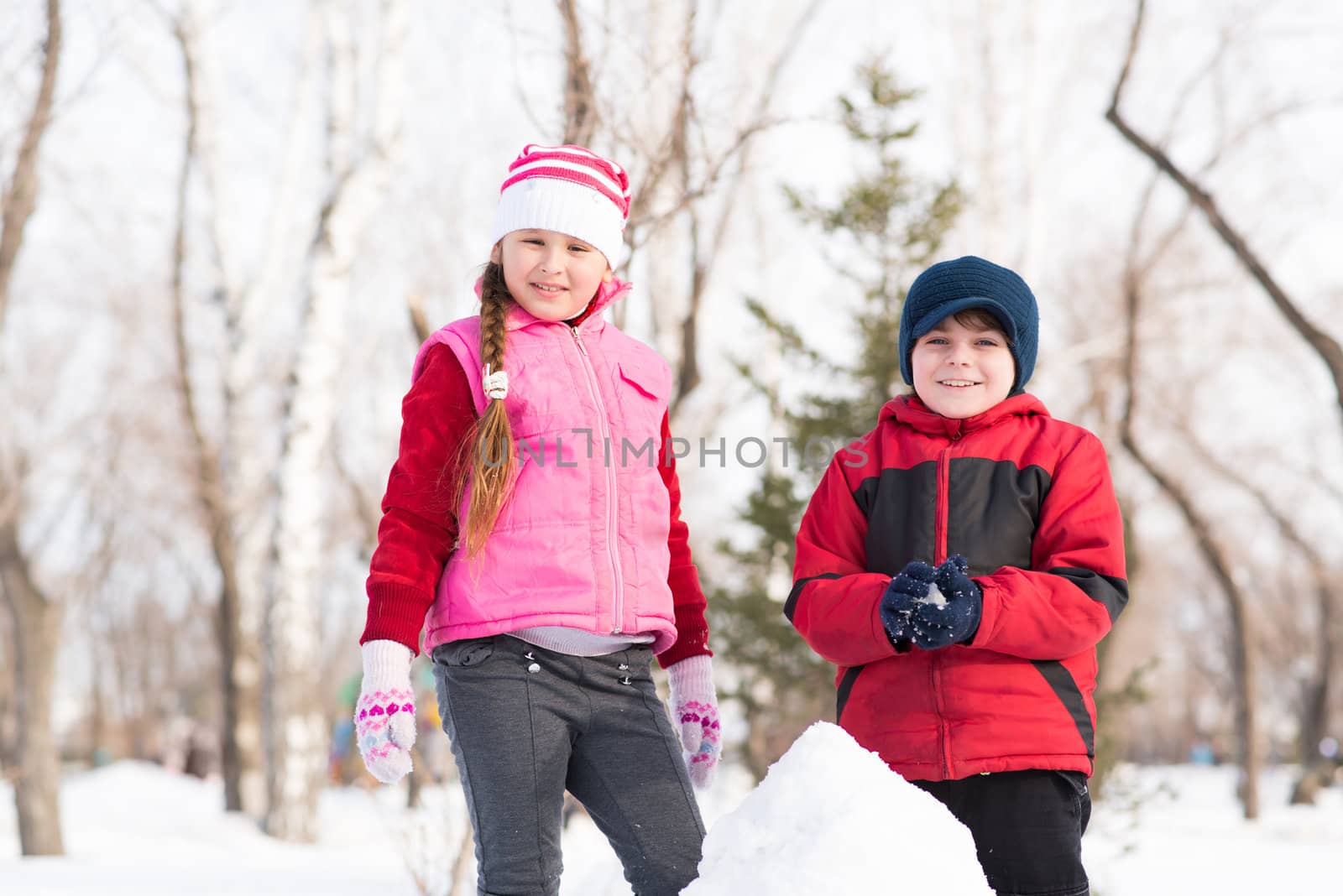 Boy and girl playing with snow in winter park by adam121
