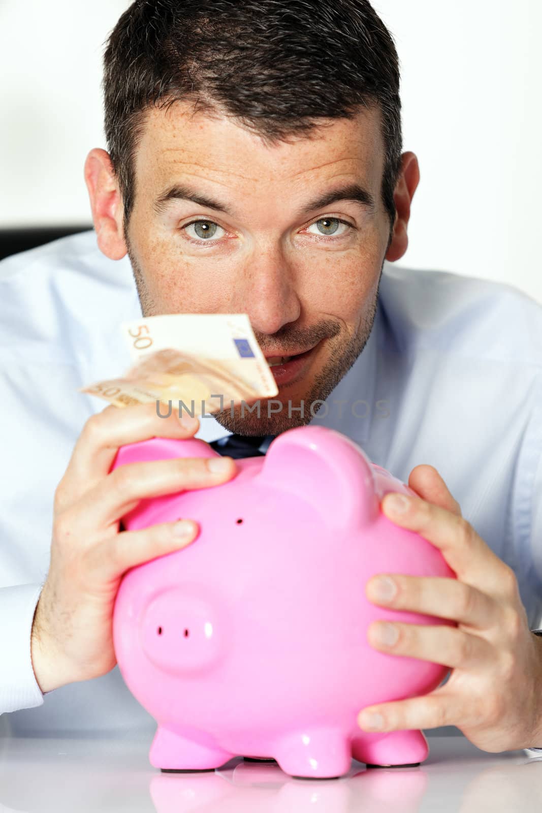 man with pink piggy bank and fifty euro banknote