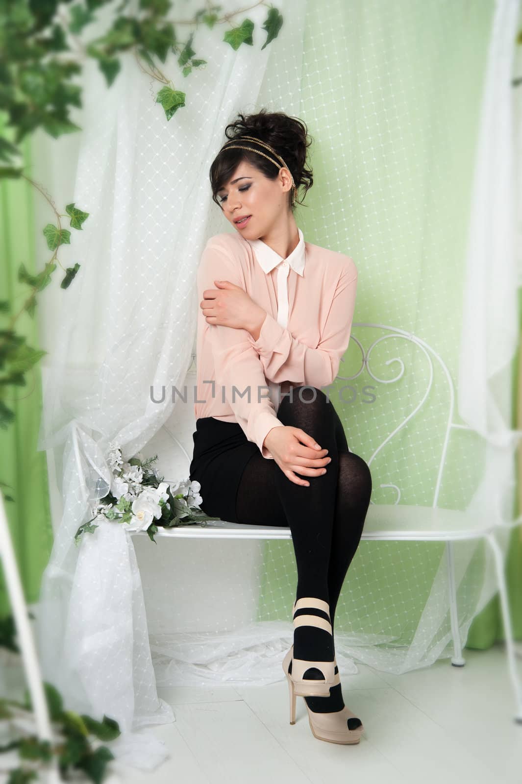 A woman in a pink blouse sitting on a bench in the green.