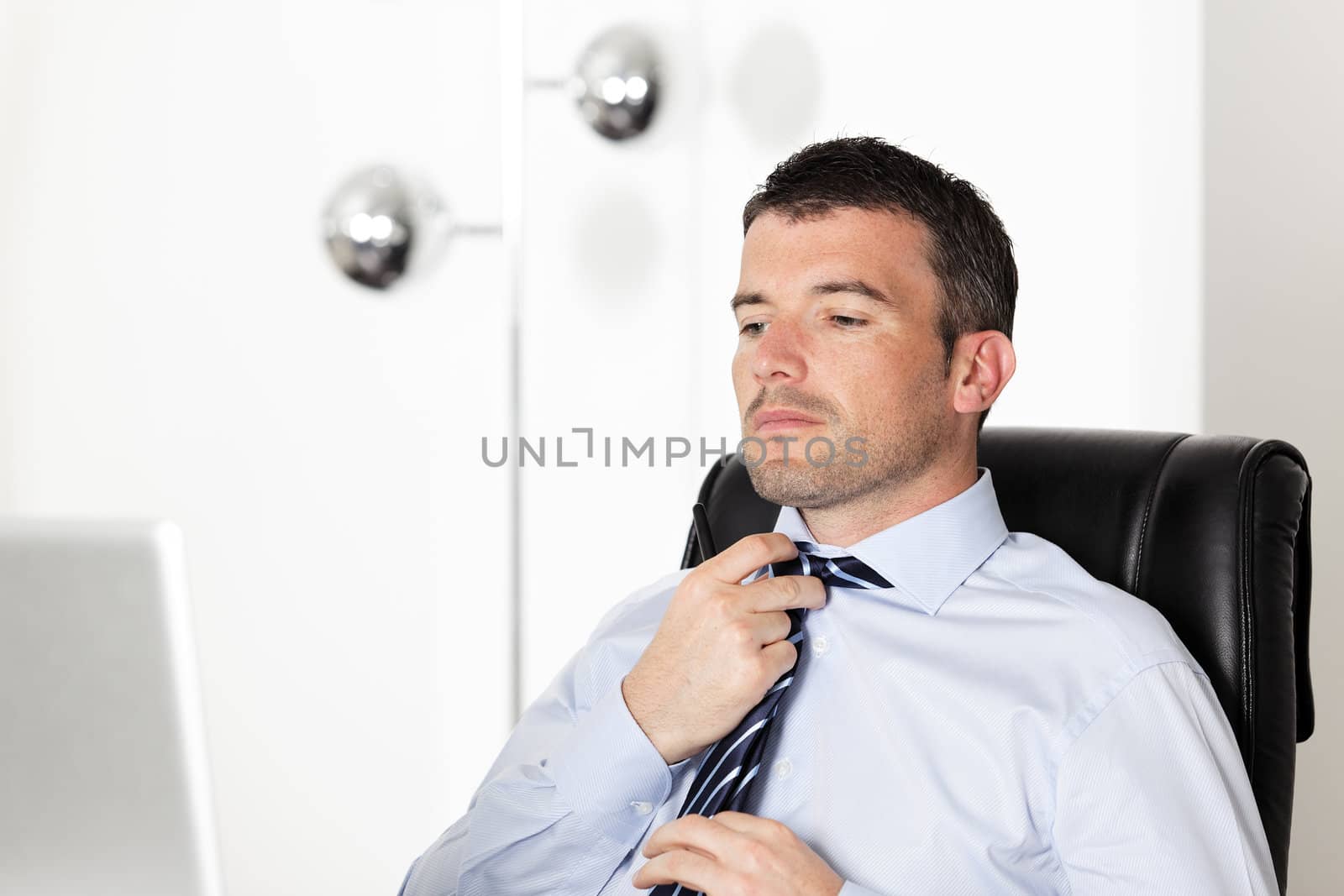 handsome businessman readjusting his tie in office