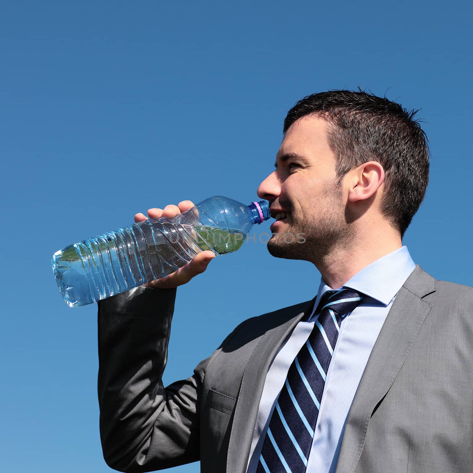 handsome businessmanman drinking water in blue sky