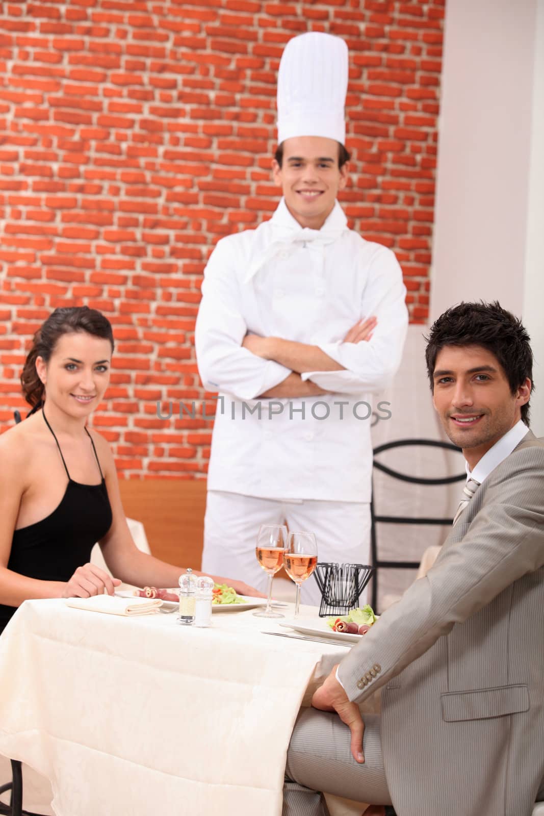 Chef stood with couple in restaurant by phovoir
