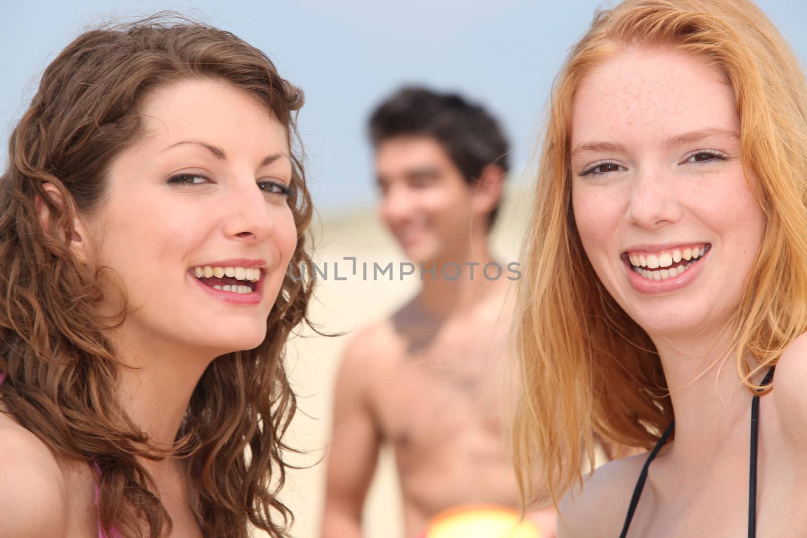 Closeup of smiling young people having fun on the beach by phovoir