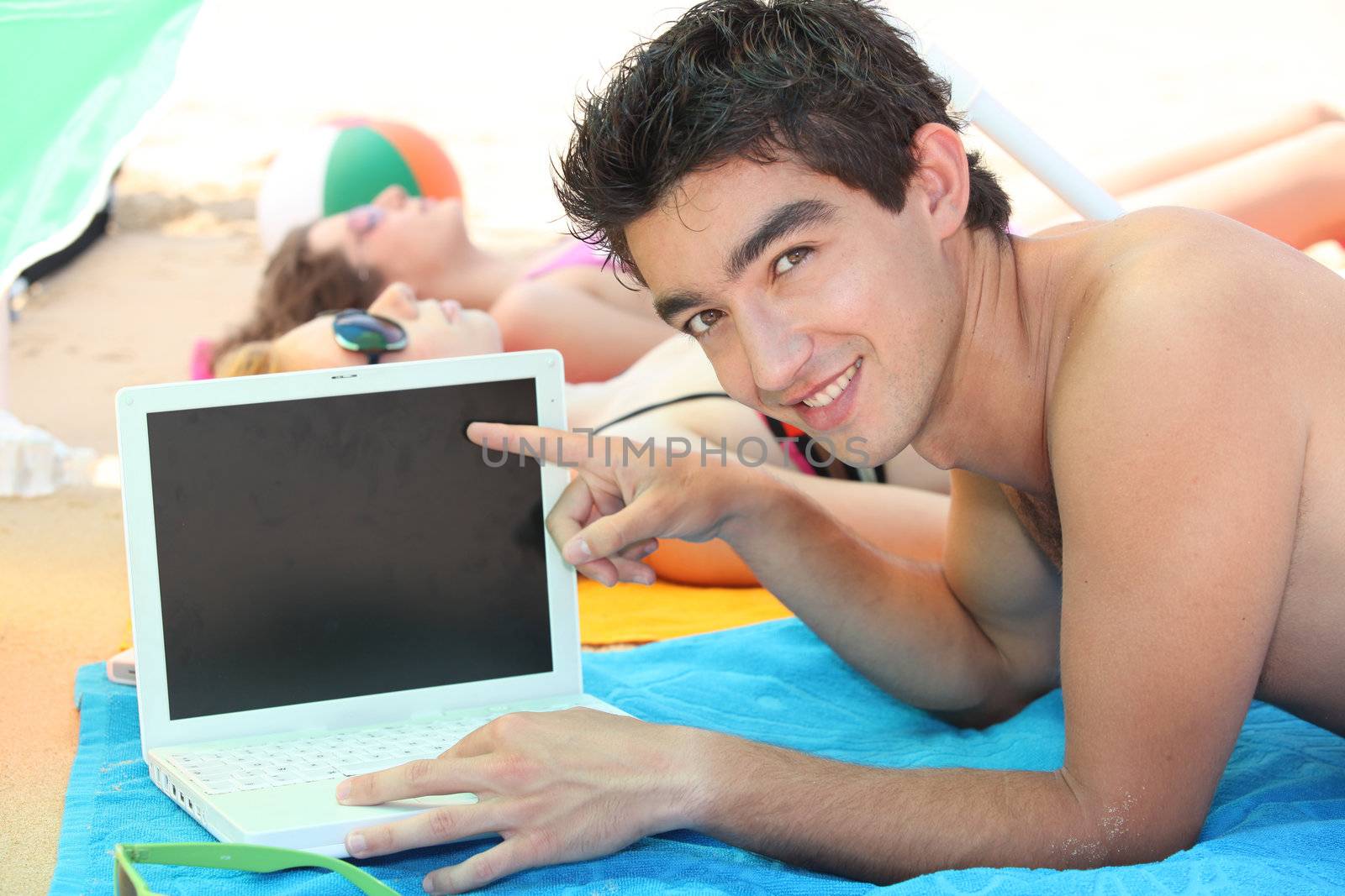 Young man on his laptop at the beach