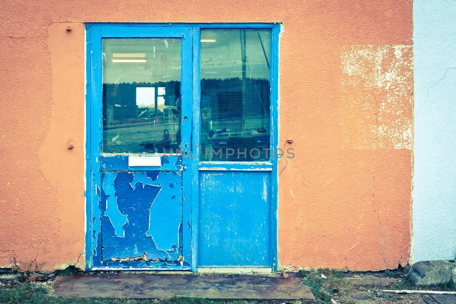 A weathered blue door in an orange wall