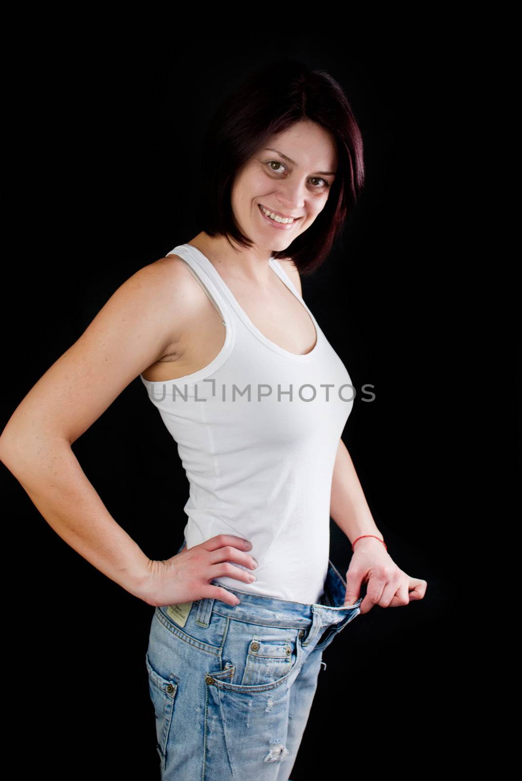 attractive caucasian woman with big jeans on black background, weight loss 