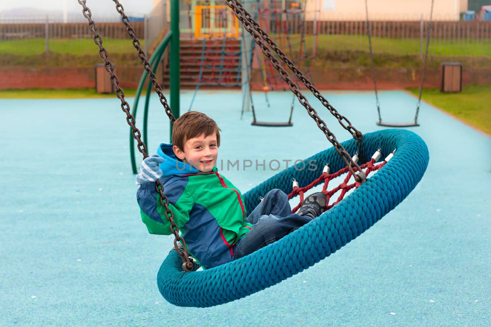 A happy young boy playing on a park swing