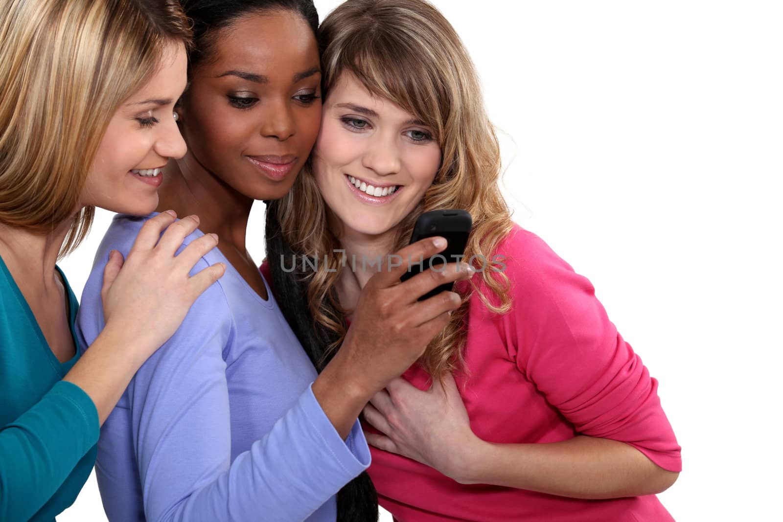 Three female friends looking at mobile telephone by phovoir