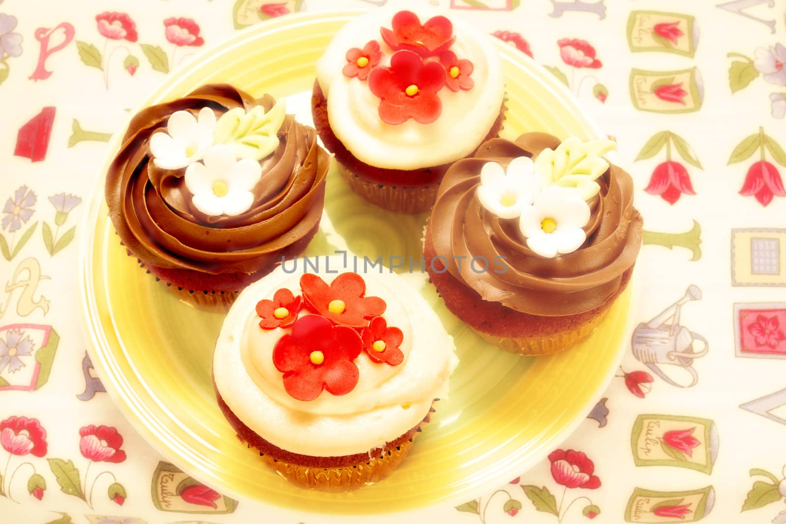 four delicious cupcakes decorated with chocolates and flowers