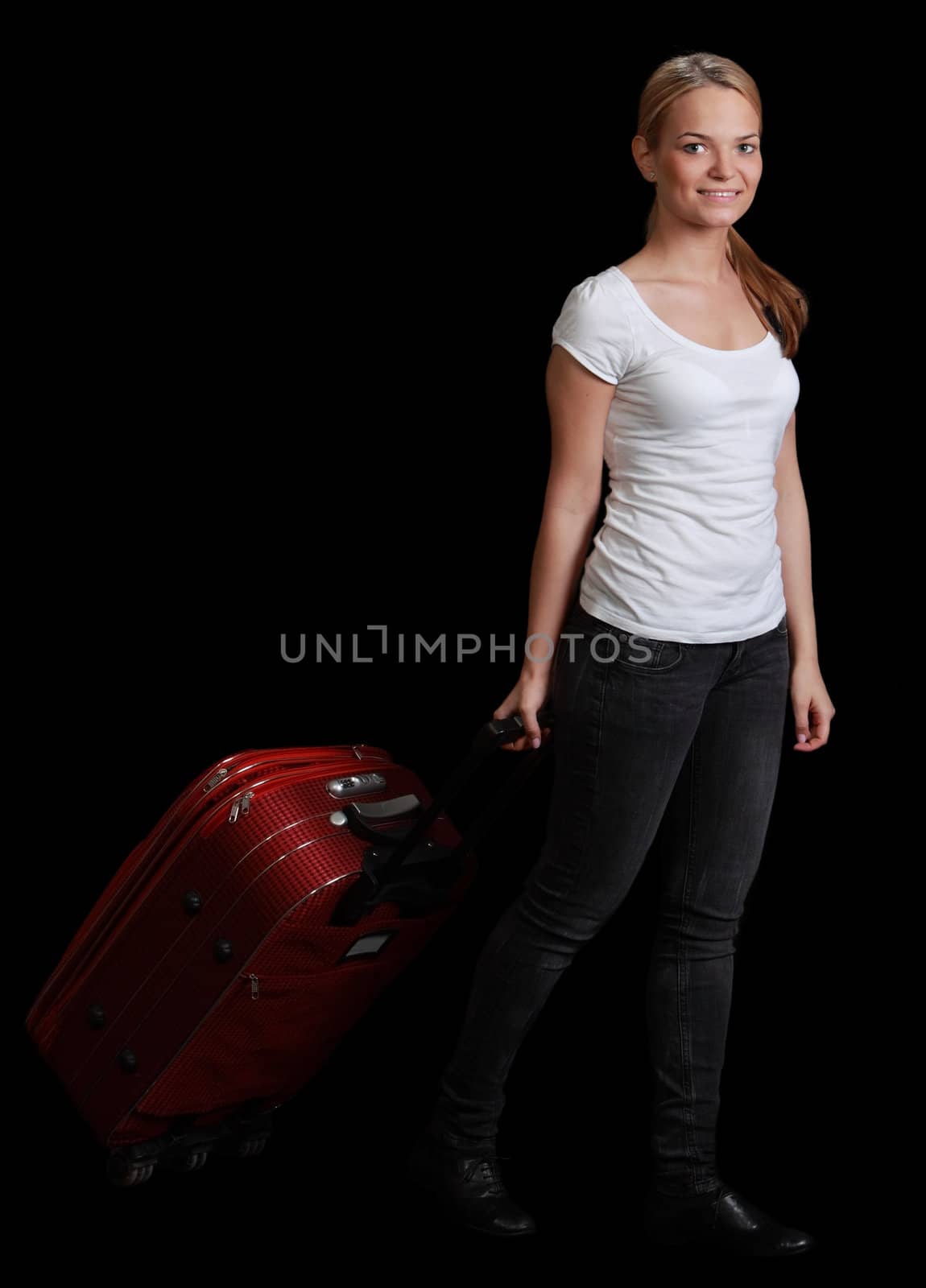 Young blonde woman with a red suitcase walking against a black background.