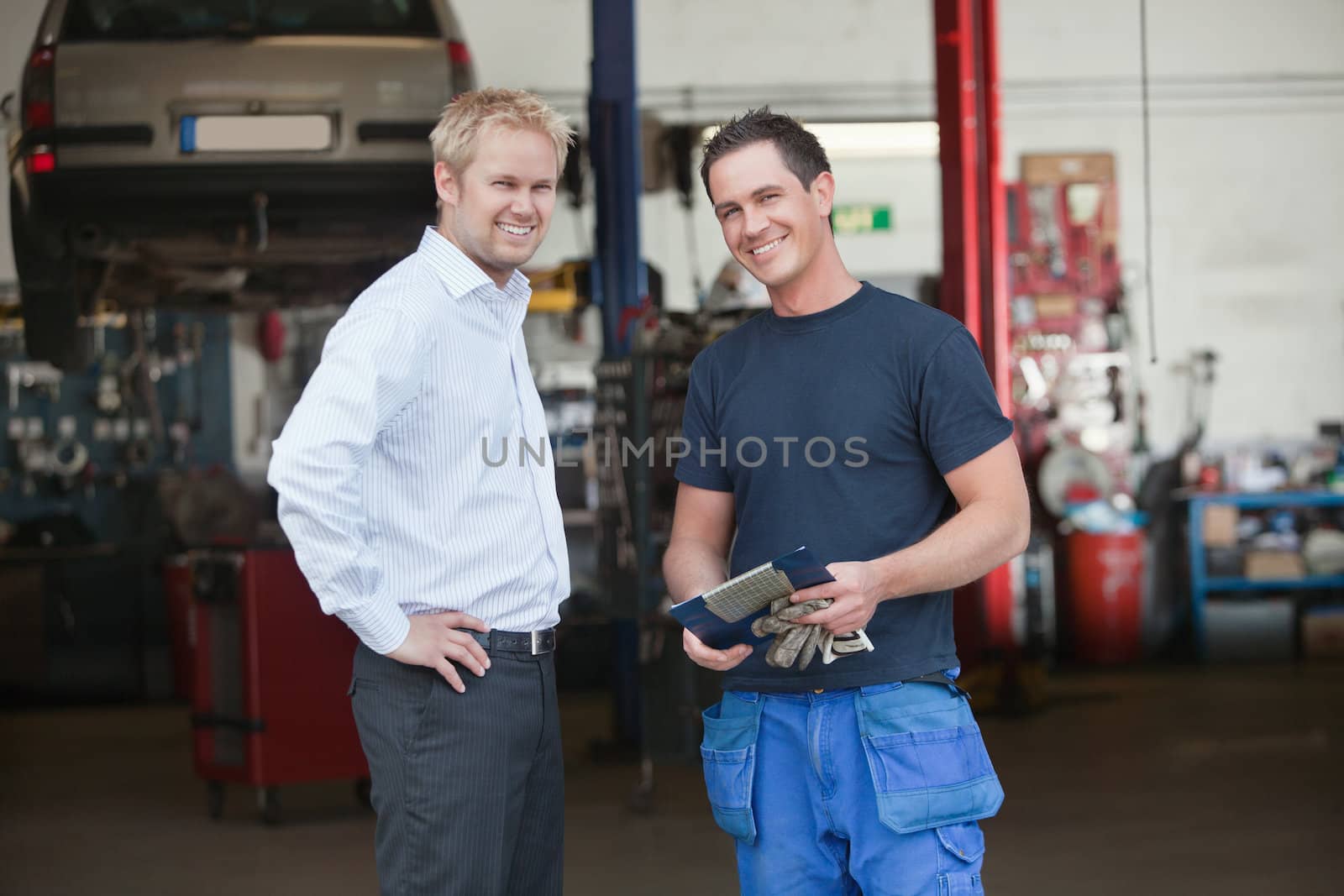 Portrait of a male customer standing with mechanic outside the garage