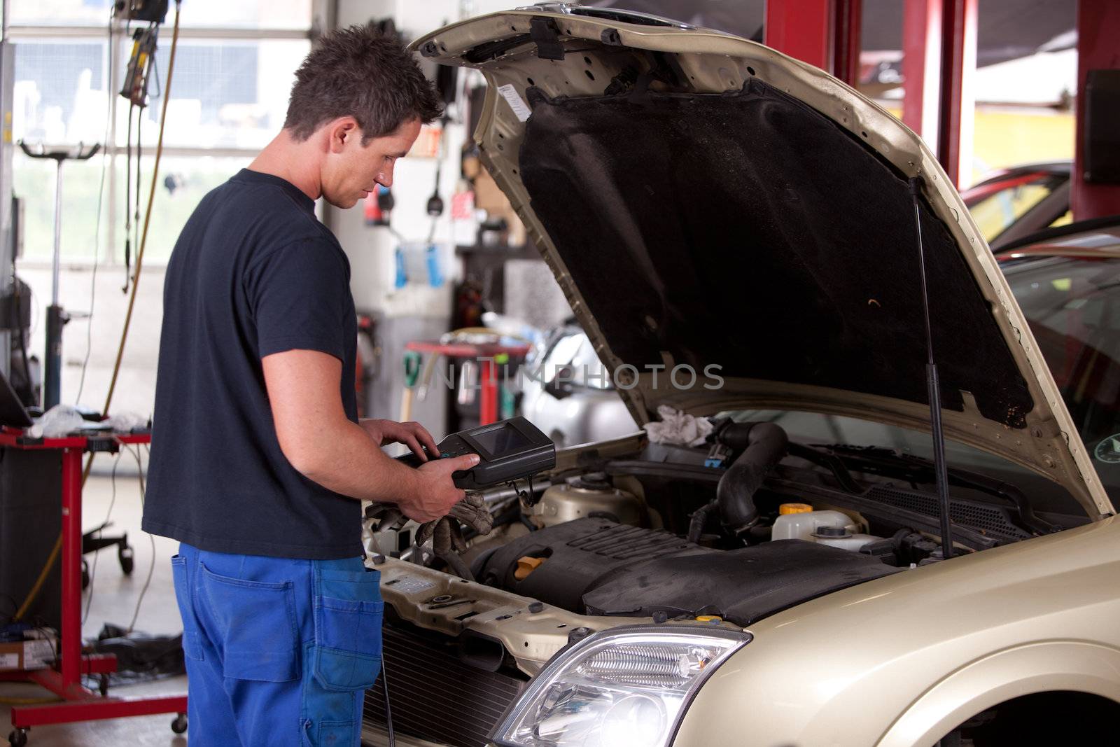 A young mechaing running a diagnostic test on a car