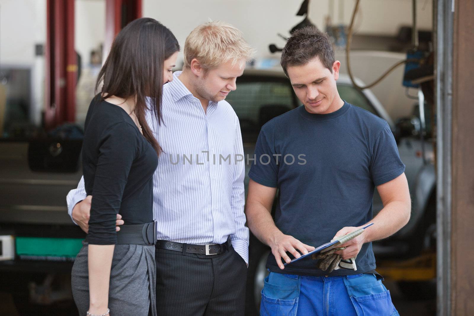 Mature couple standing with mechanic outside the garage