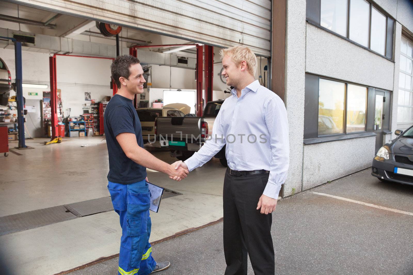 Mechanic shaking hands with client by leaf
