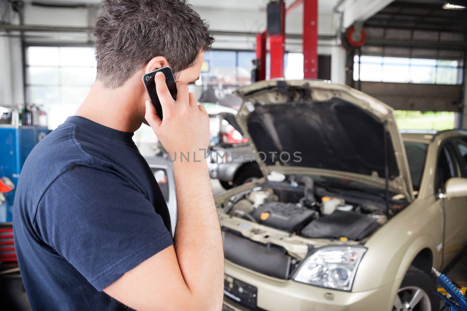 Mechanic talking on cell phone by leaf