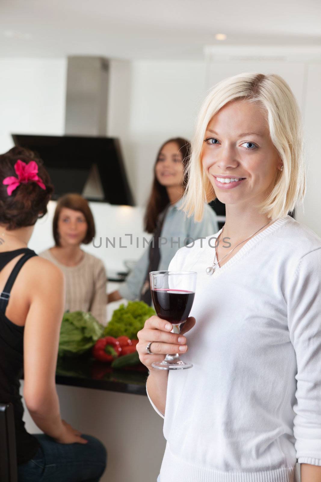 Portrait of pretty woman holding glass wth female friends in background