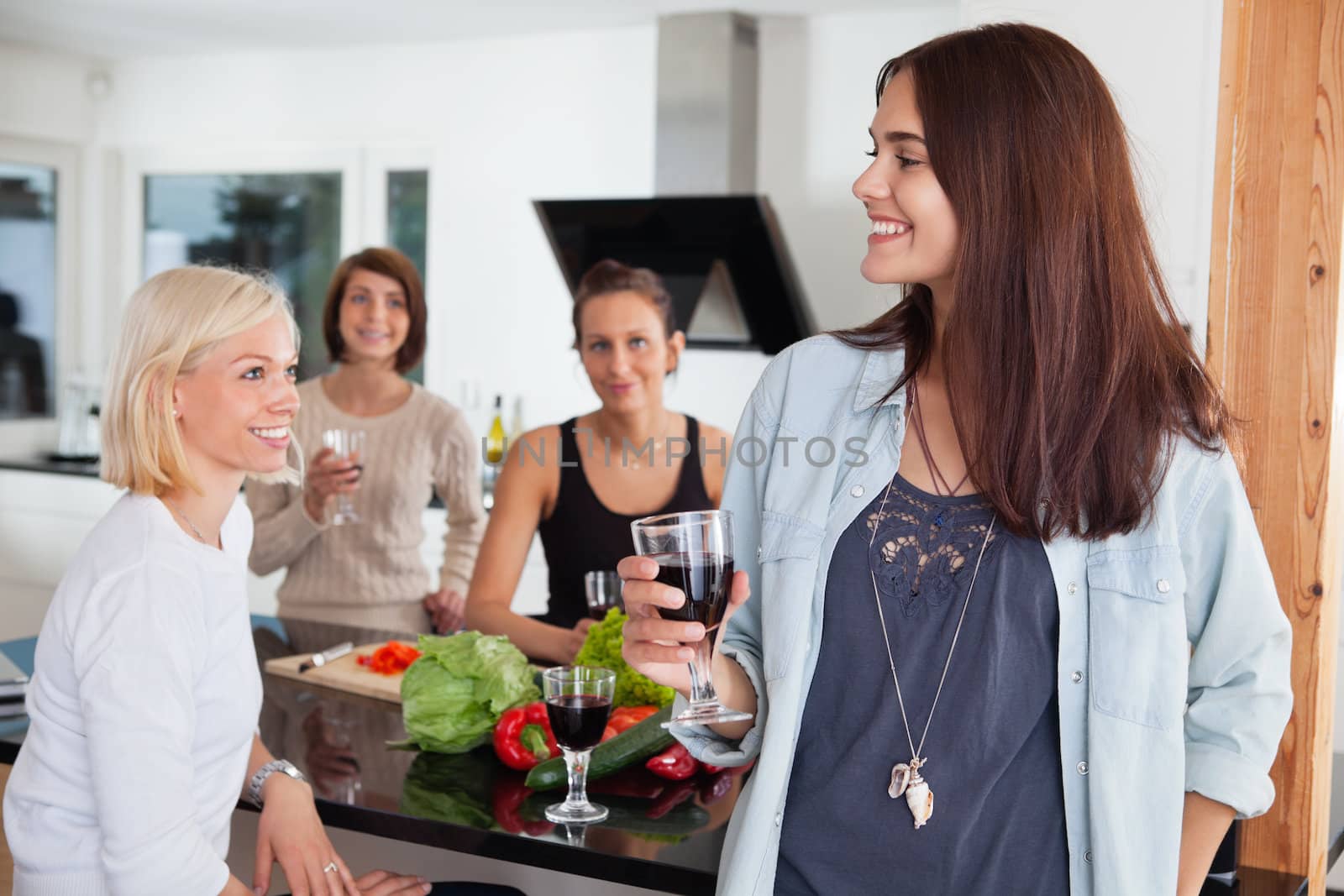 Female friends enjoying drink in kitchen by leaf