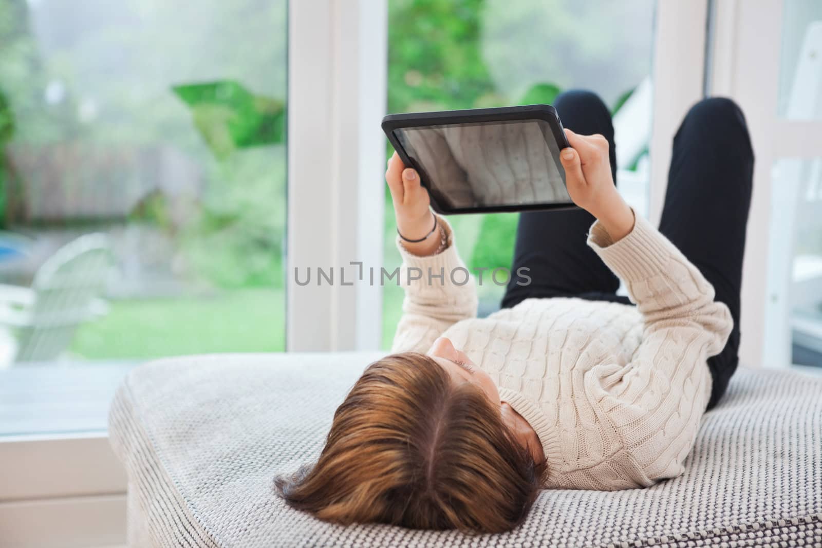 Woman holding tablet pc while lying on sofa at home