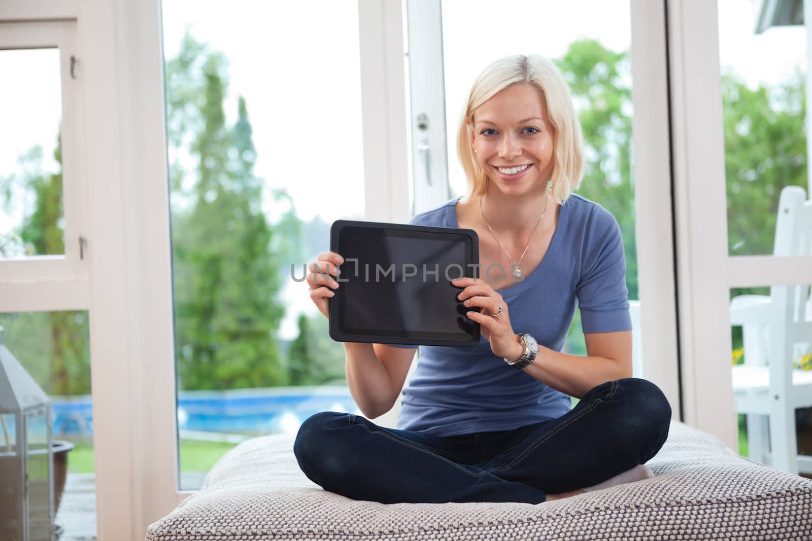 Portrait of happy young female holding tablet pc while sitting on couch