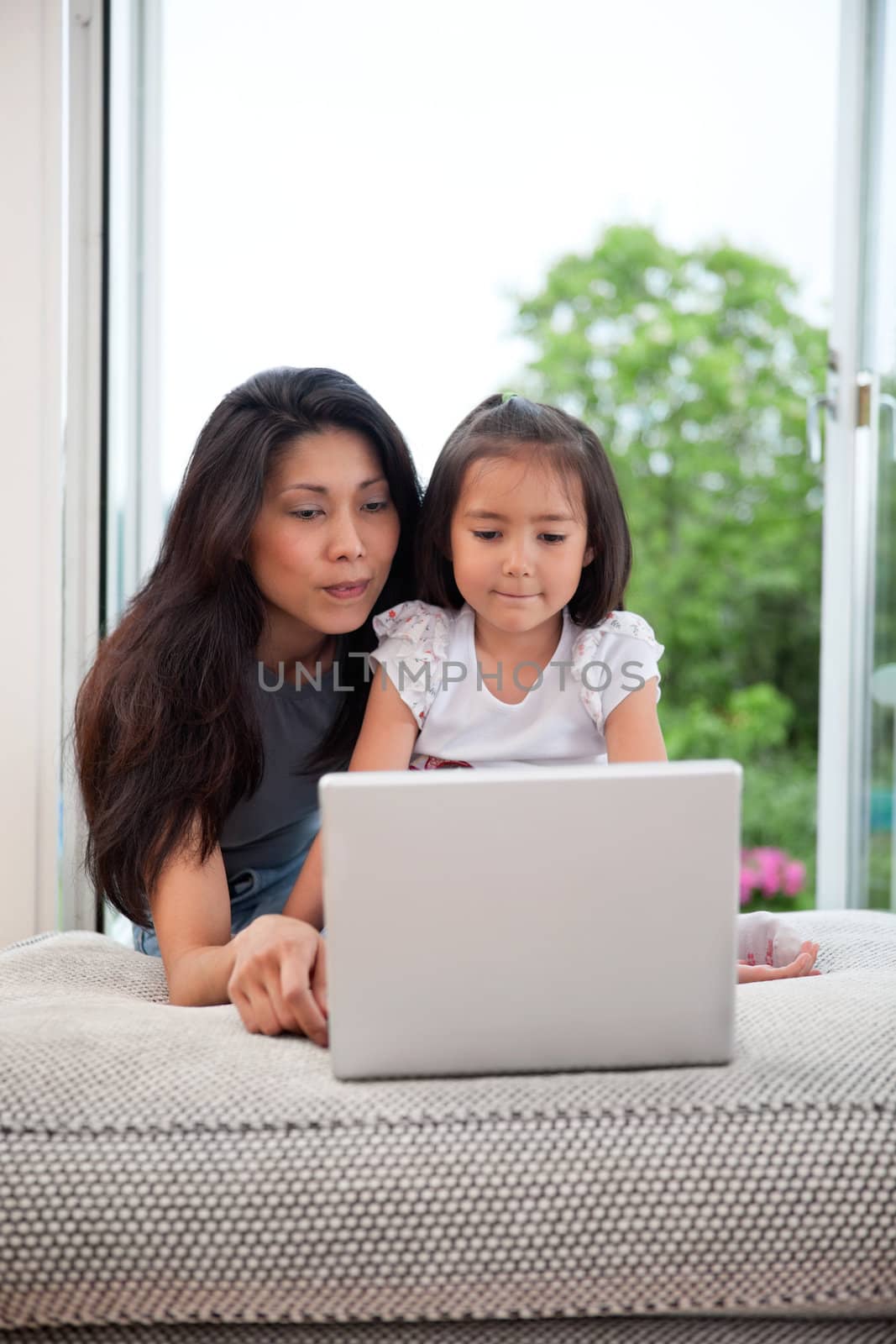 Mother and daughter with laptop by leaf