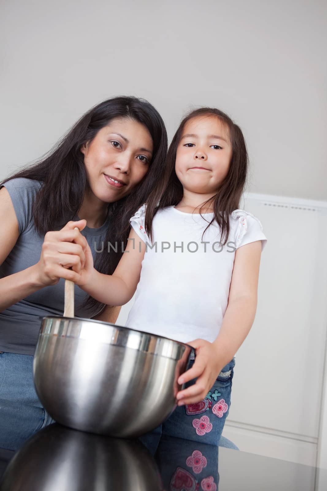 Portrait of smiling mother and cute little daughter in kitchen
