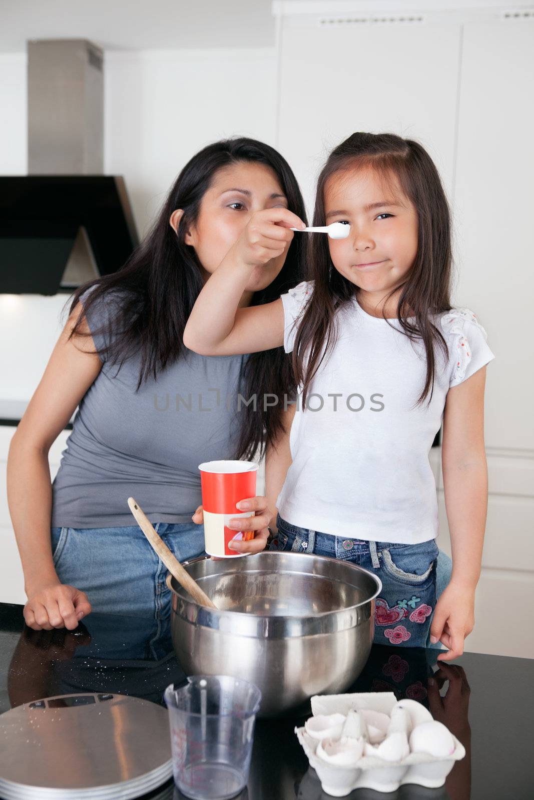 Mother and daughter in kitchen by leaf