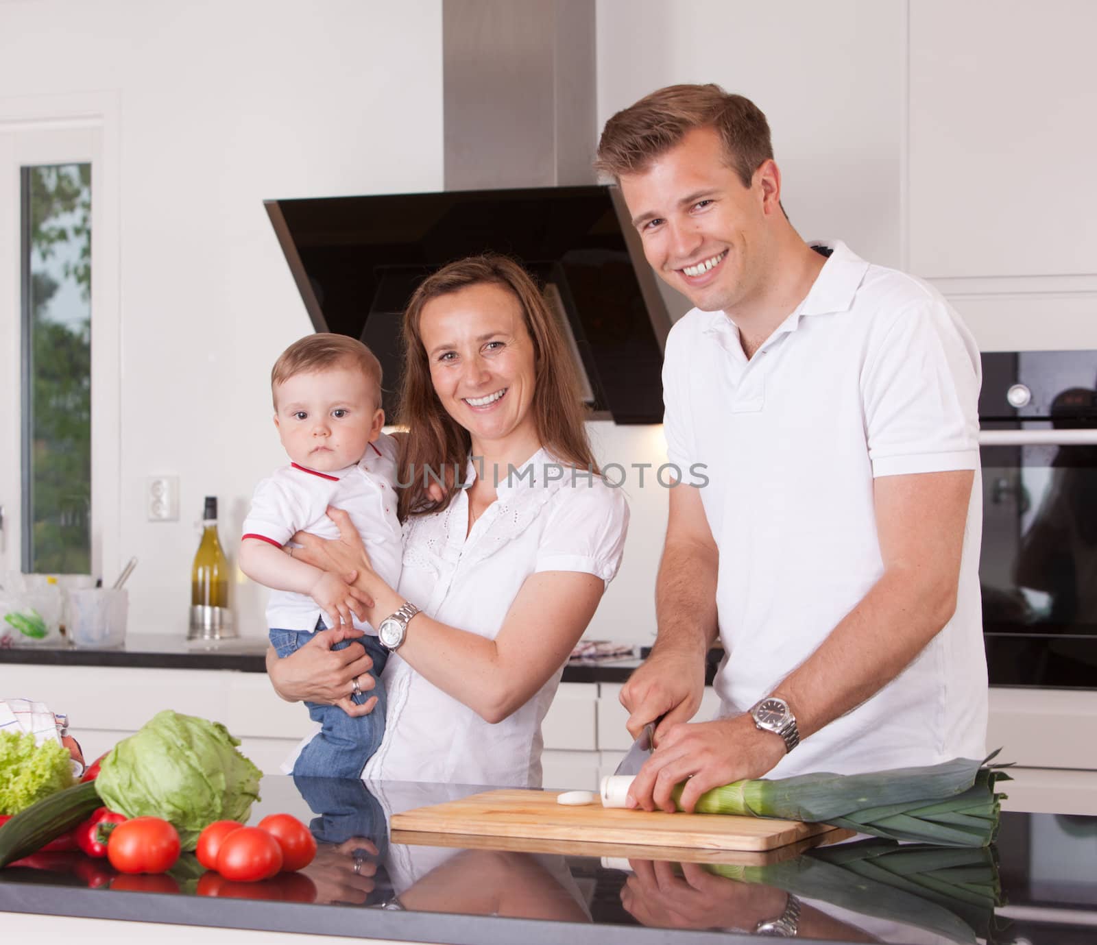 A happy family cutting vegetables in a kitchen, looking at the camera