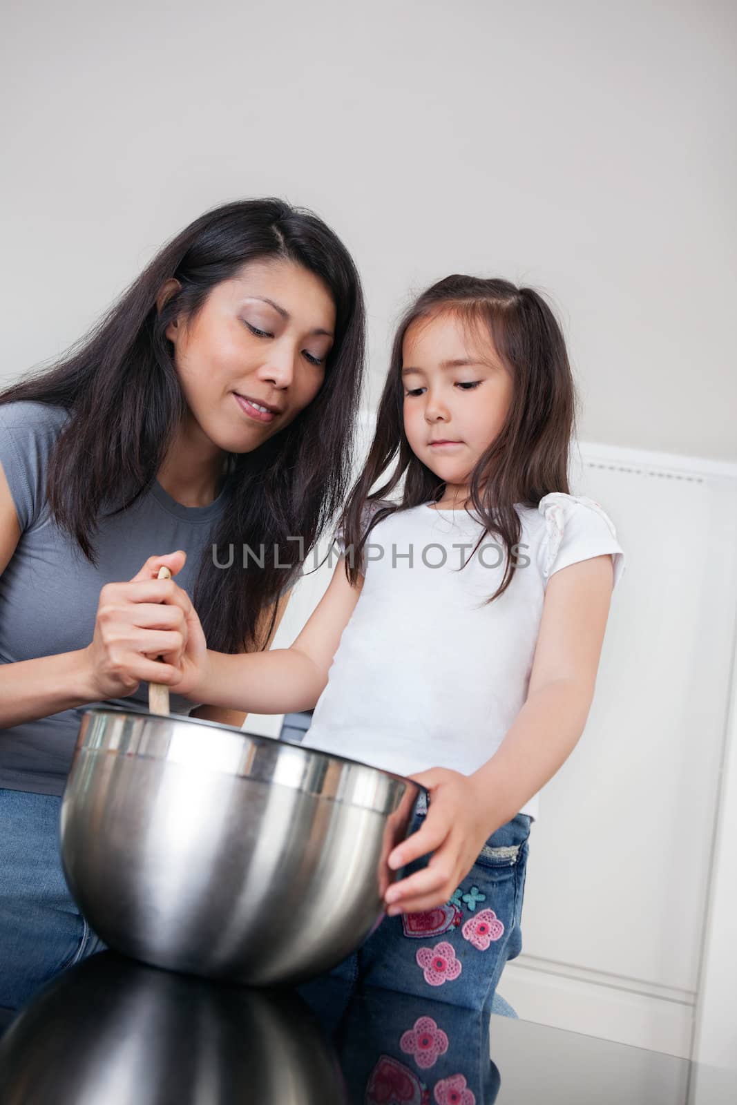 Mother and daughter in kitchen baking by leaf