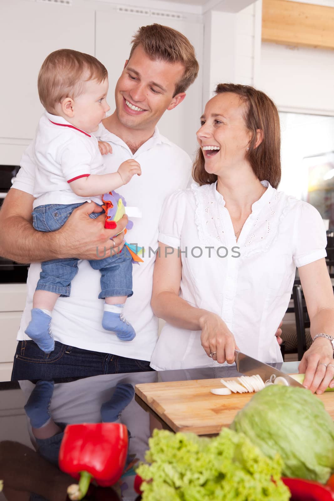 Happy family with young toddler boy, making foodin the kitchen and having fun