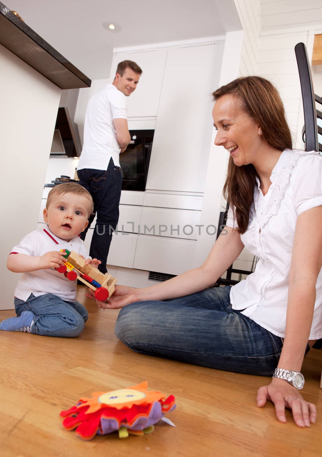 Happy family with son playing on floor with mother and father in the background