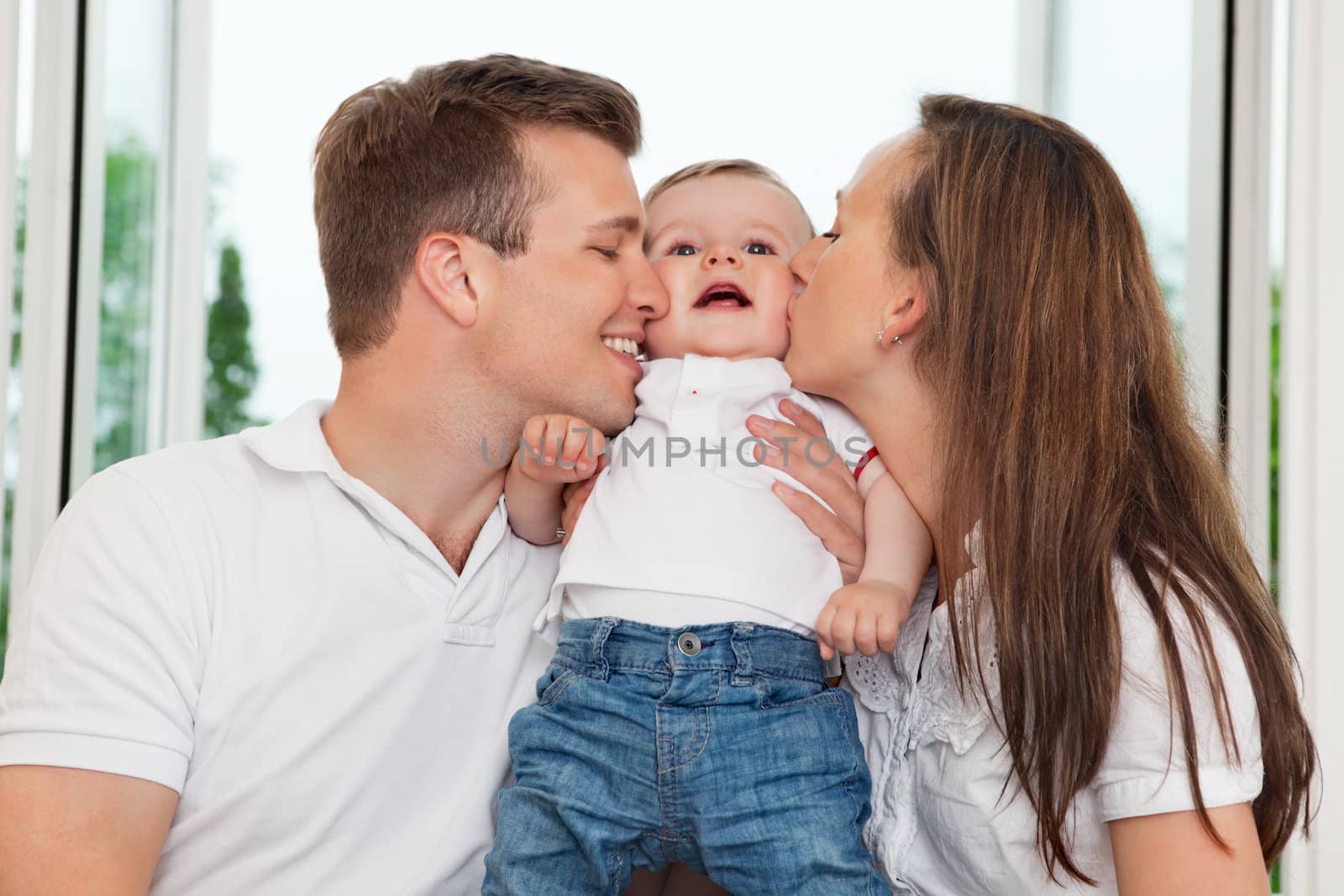 Close-up of mother and father kissing their child