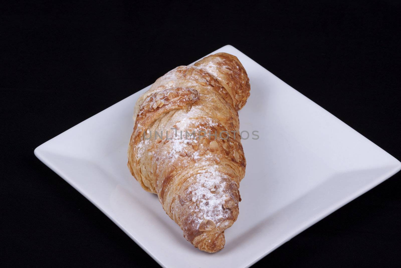 fresh almond croissant isolated on a black background