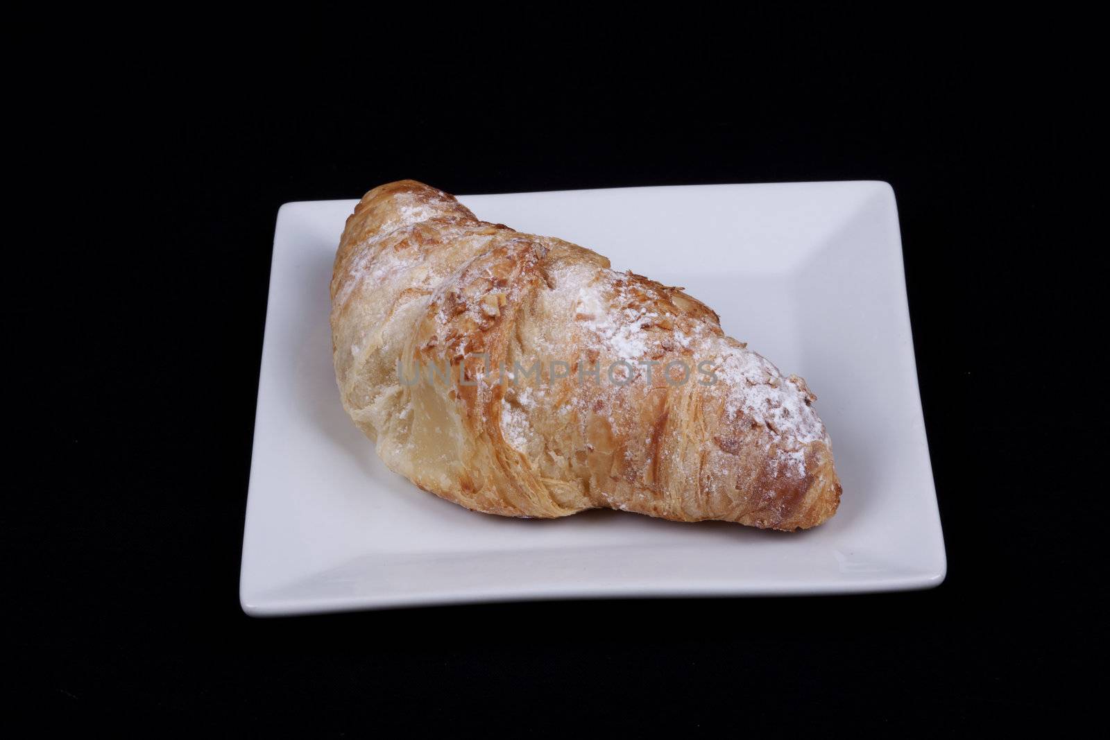 fresh almond croissant isolated on a black background