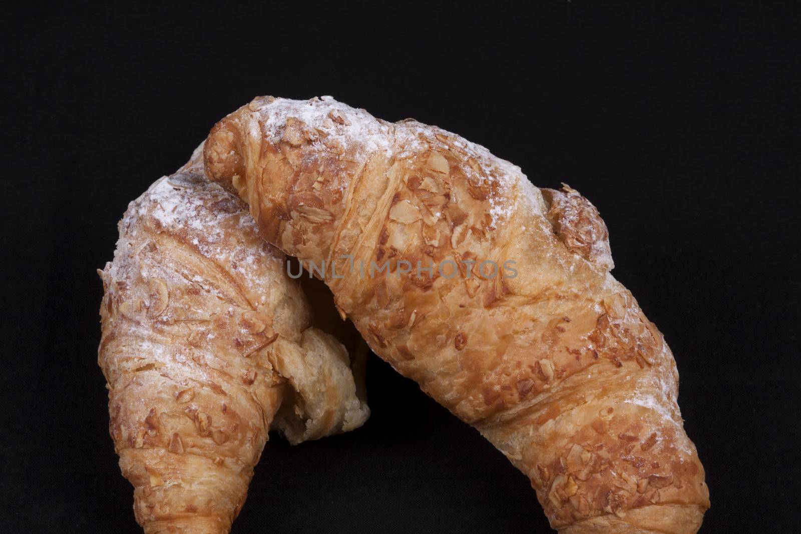 fresh almond croissant isolated on a black background