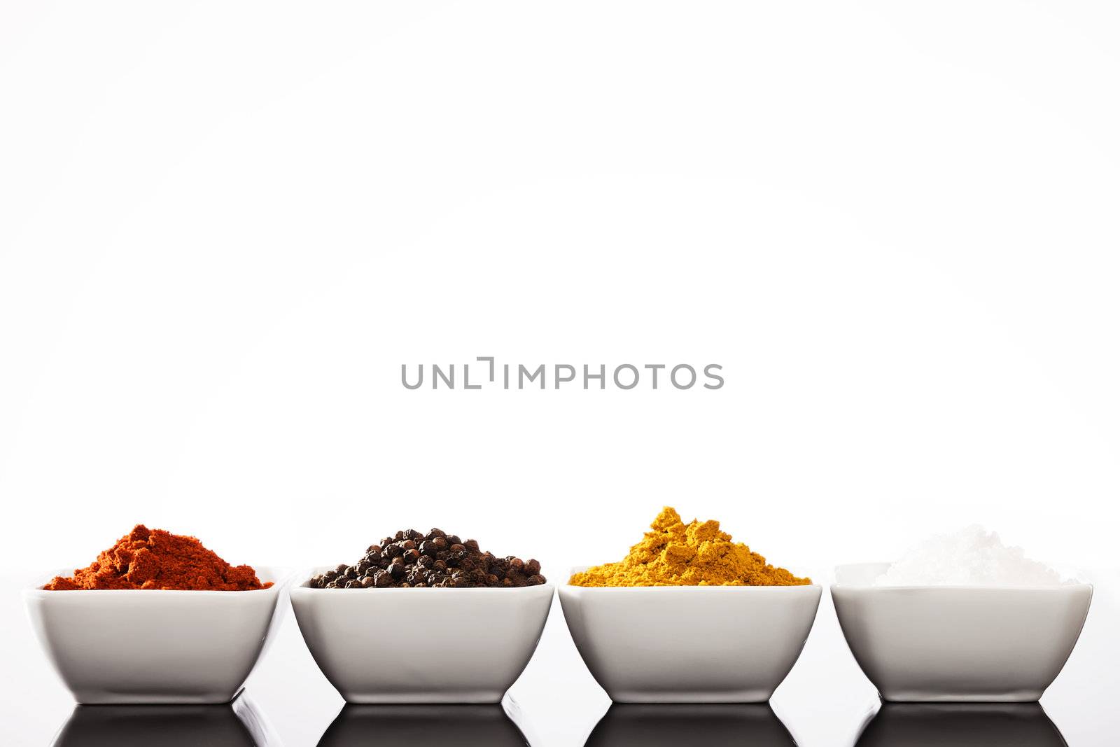 row of small bowls filled with pepper peppercorns curry and salt spices 