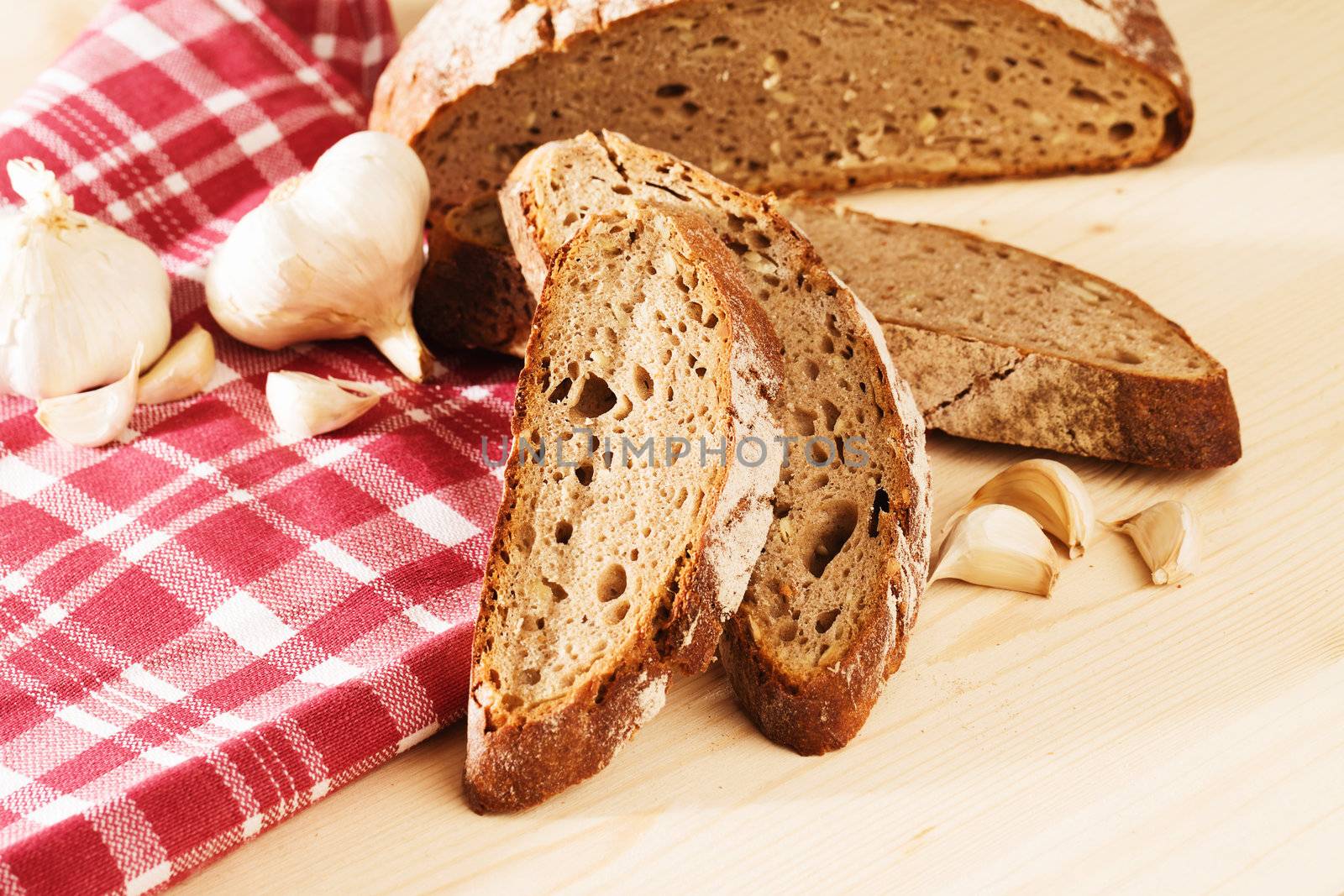 rye bread with garlic and a towel on wooden background