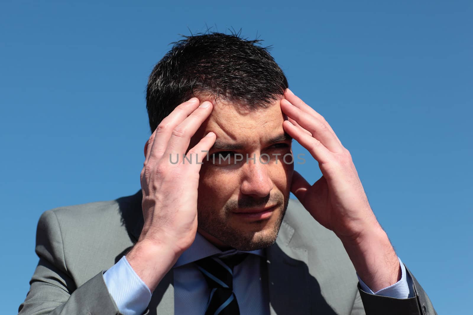 businessman with head in the hands in blue sky