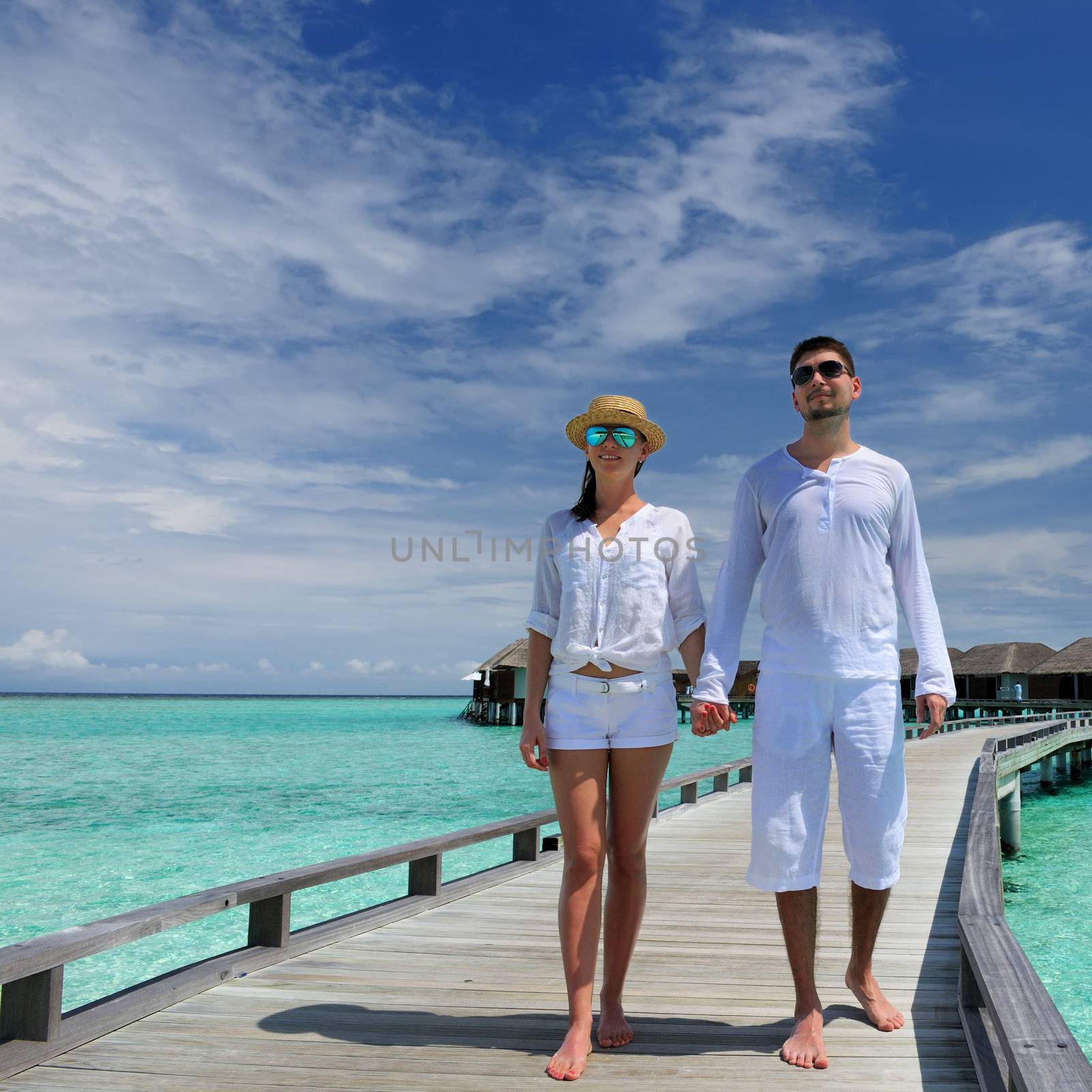 Couple on a tropical beach jetty at Maldives