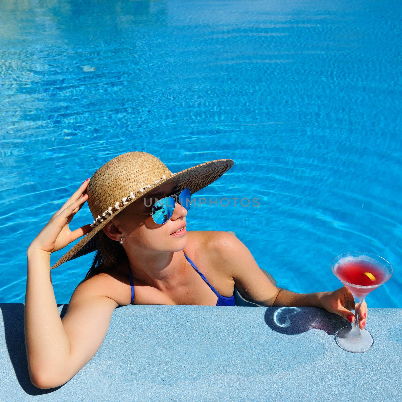 Woman at poolside with cosmopolitan cocktail by haveseen