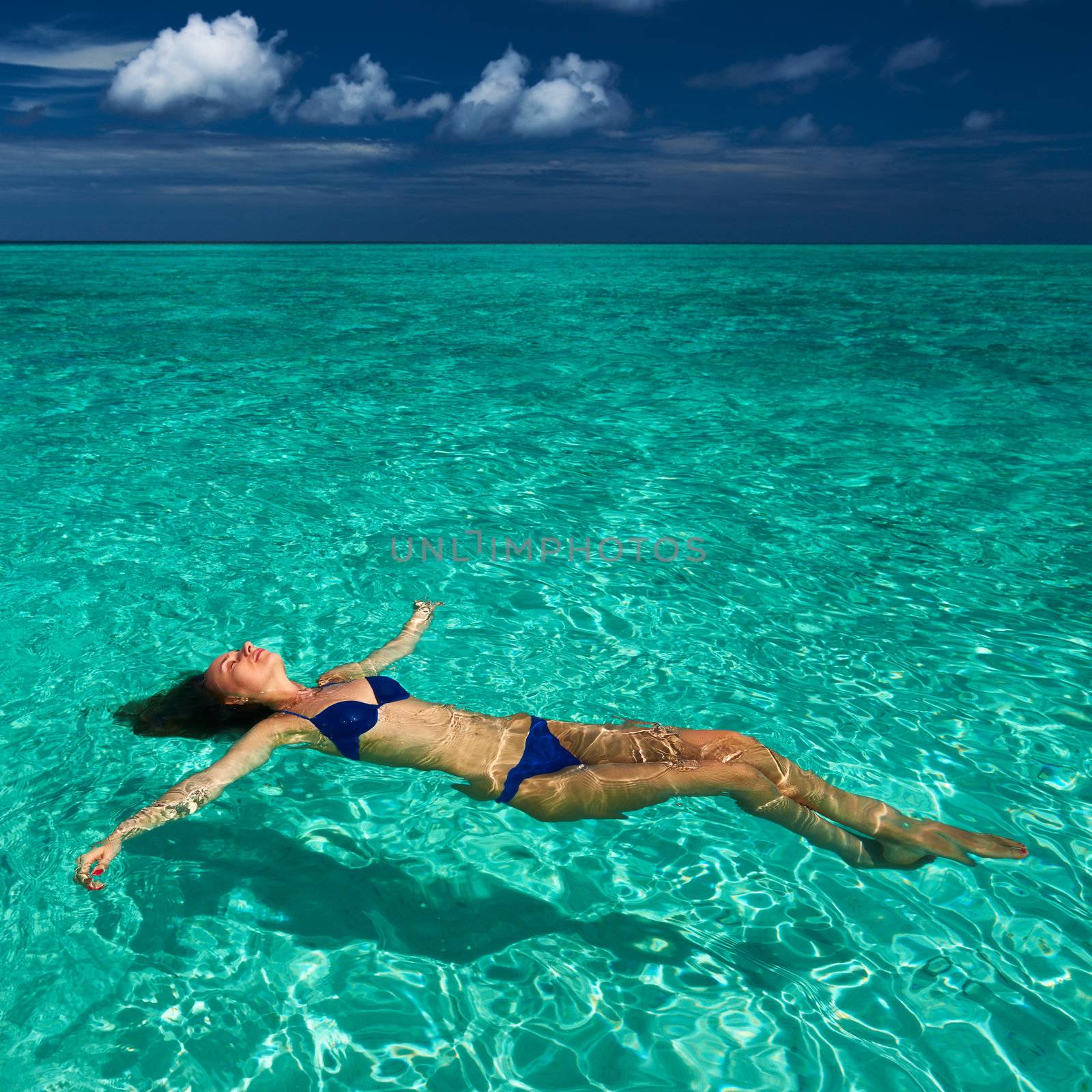 Woman in bikini lying on water  by haveseen