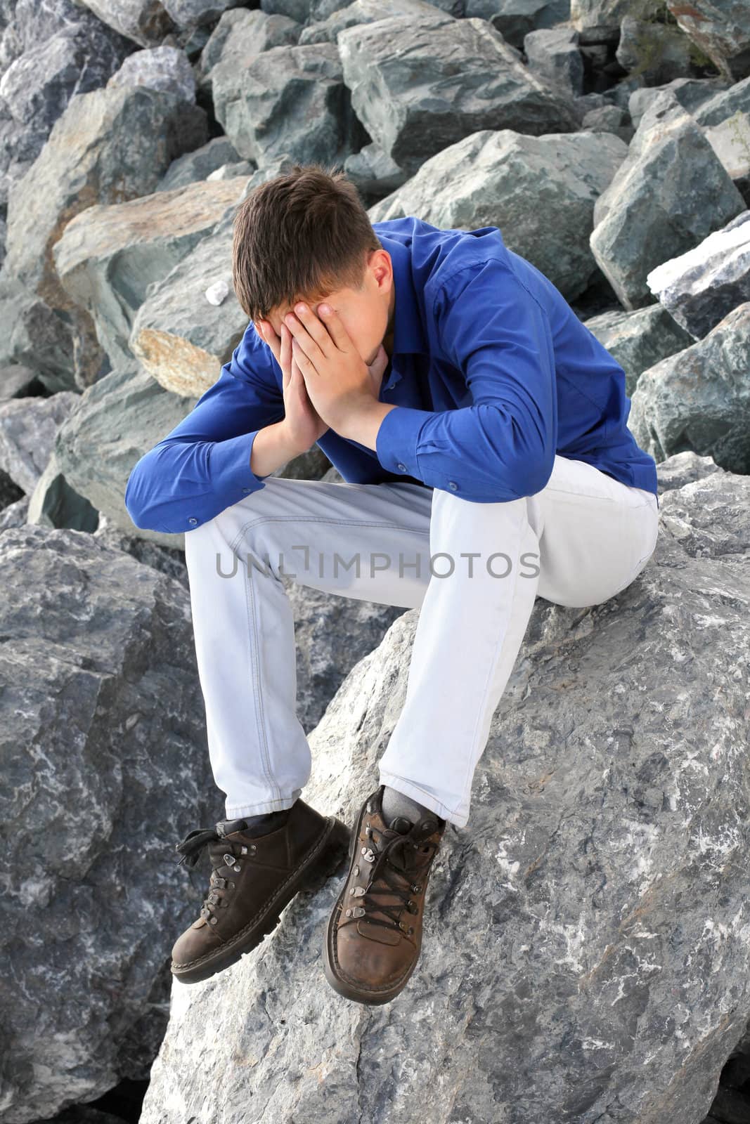 sad teenager sitting on the rocks