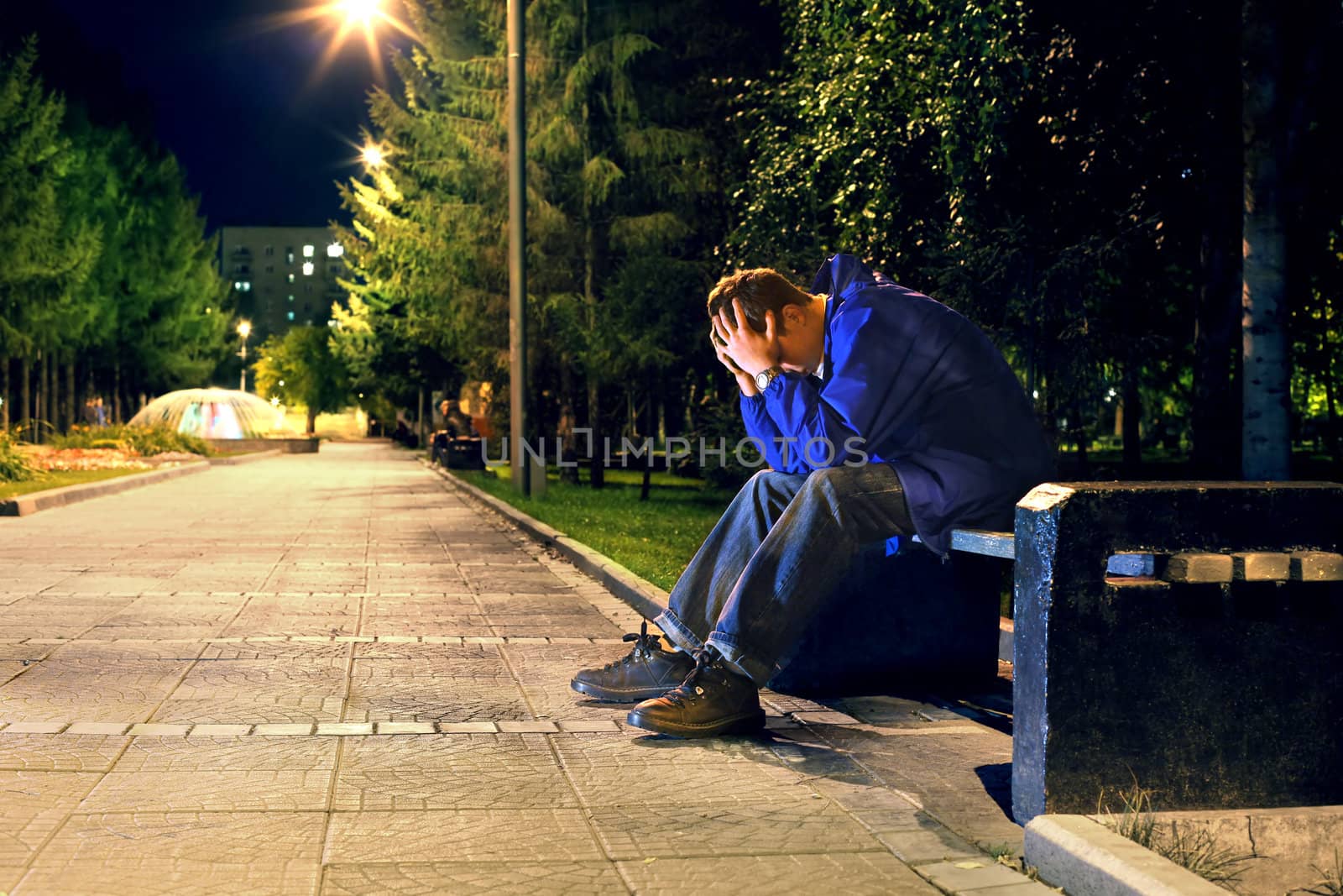 troubled teenager with hidden face sitting in the night park