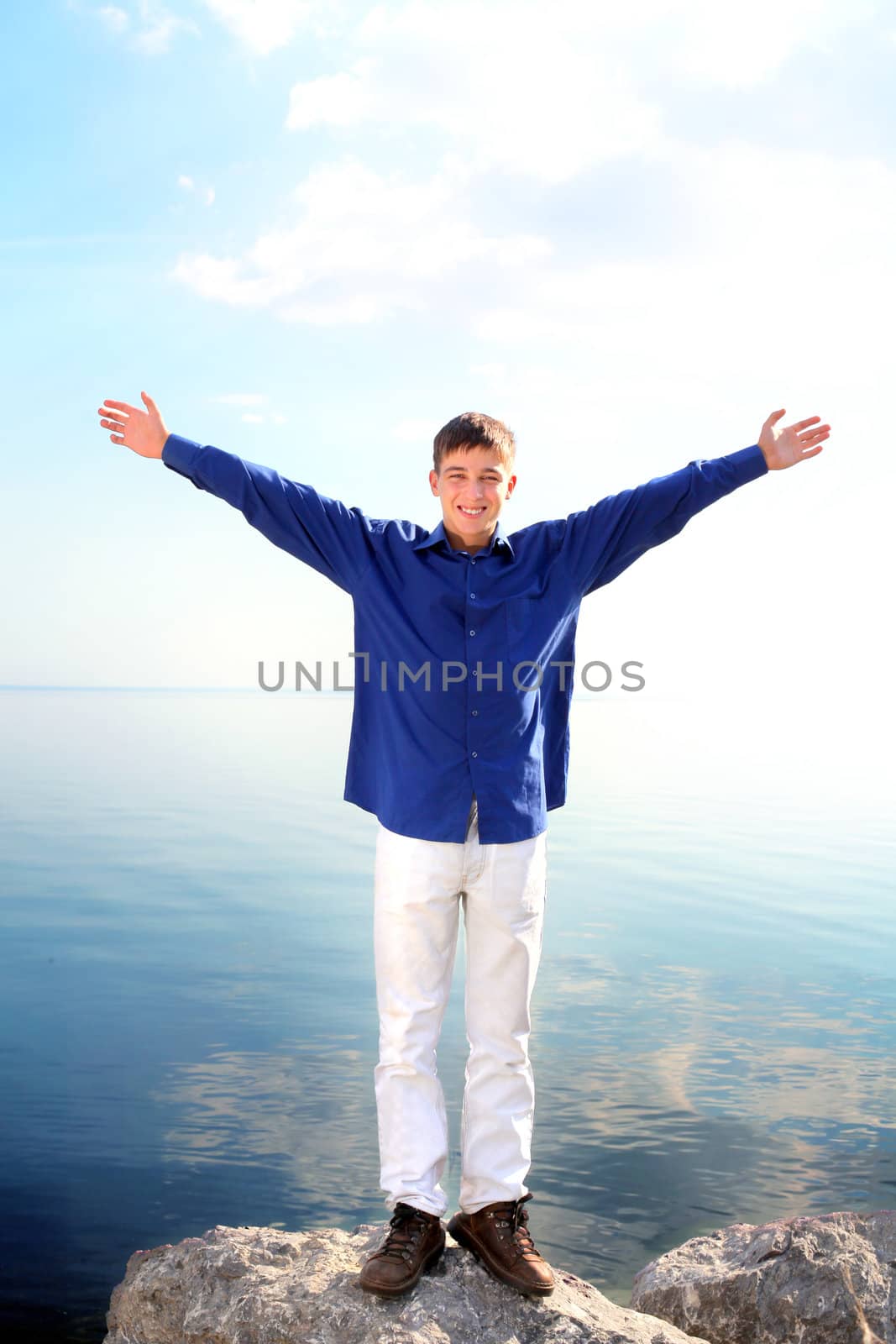 happy young man with hands up on the seaside background