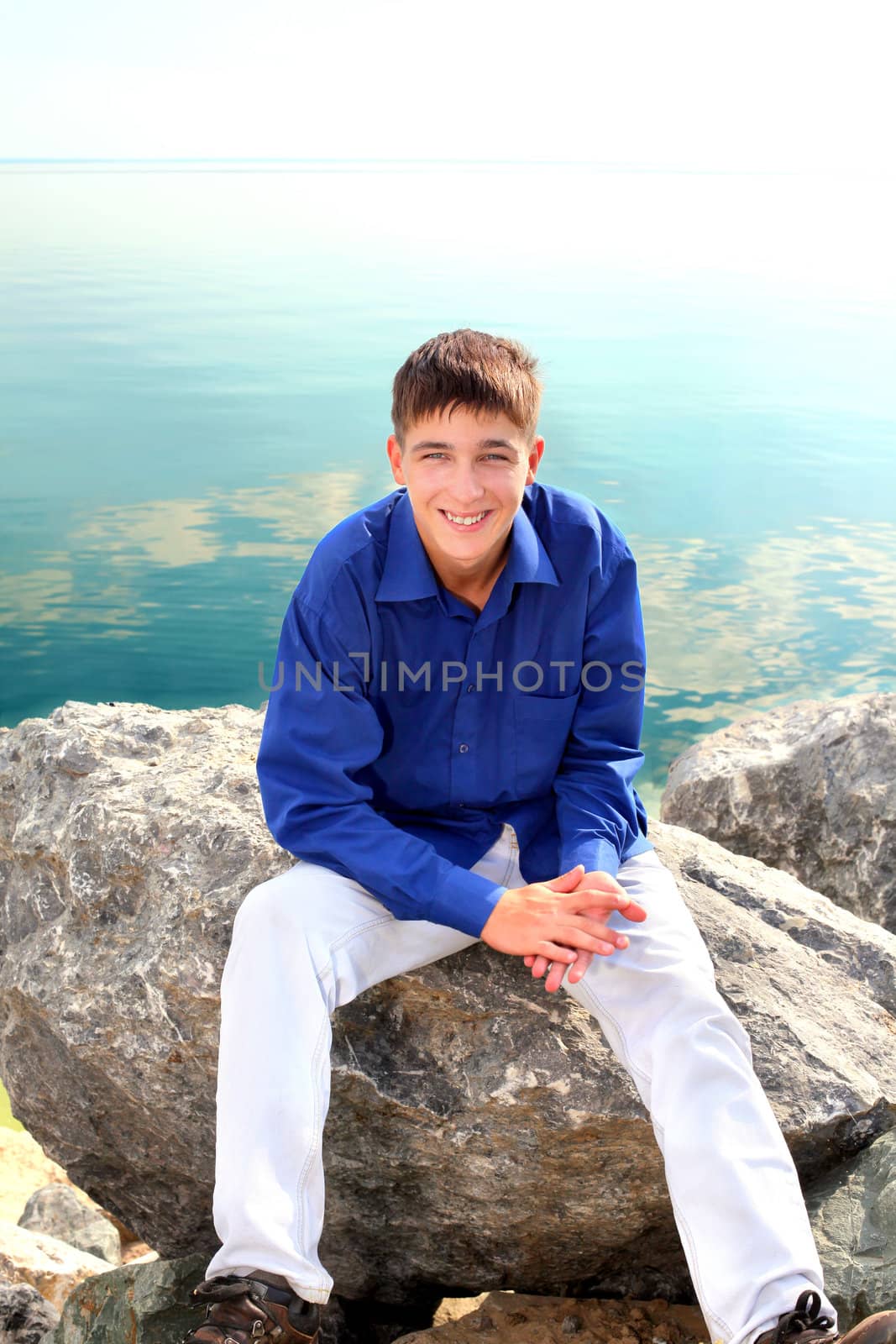 happy teenager sitting near the water